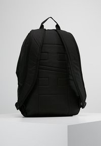 Zaino nero con pannello posteriore imbottito, spallacci regolabili, tasche laterali in rete e design minimalista. Tessuto resistente con cuciture rinforzate.