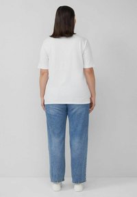 White cotton t-shirt with short sleeves, paired with light blue high-waisted jeans and white sneakers. Simple, casual design.