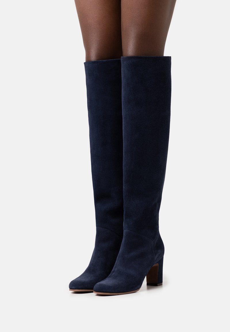 Knæhøje navy suede støvler med en rund tå og en chunkyhæl. Glat tekstur og minimal detaljer.