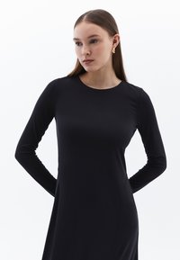Schwarzes langärmliges Kleid mit rundem Ausschnitt, ausgestattet mit einer glatten Stoffstruktur und gerader Silhouette, geeignet für verschiedene Anlässe.