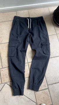 Mörkblå cargobyxor med elastisk midja, vit dragsko, sidofickor och elastiska muddar. Tillverkade av ett lätt material med en mjuk yta.