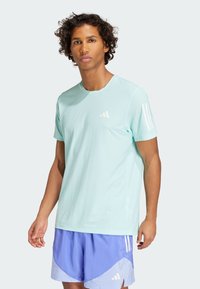 T-shirt de sport bleu clair en tissu respirant, avec un col rond et un logo blanc sur la poitrine, ainsi que des rayures sur les manches.