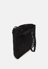 Sac fourre-tout noir en toile avec de longues poignées, de forme rectangulaire, arborant un logo blanc audacieux sur un côté et un haut ouvert pour un accès facile.