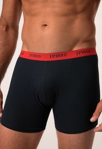 Mustat boxerit, jotka on valmistettu puuvillasta, punaisella joustavalla vyötärökaistalla, jossa on painettuna "JP1880" mustalla. Sujuva rakenne ja istuva muotoilu.