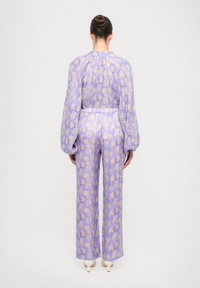 Pyjama-set med en lavendelfärgad bakgrund med ett blommönster, långa ärmar, elastisk midja och vida byxor. Slät tygtextur.