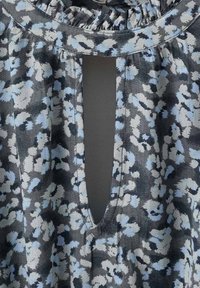 Hlavný šev z kvetinového vzoru s okrúhlym výstrihom a prešívaním. Obsahuje odtiene šedej a svetlomodrej s centrálnym kľúčovým otvorom.