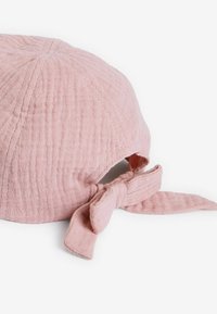 Helle pinke Baumwollmütze mit einer strukturierten Oberfläche, ausgestattet mit einer gebundenen Schleife am Rücken und einem abgerundeten Oberteil.