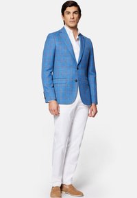 Jasnoniebieska marynarka w kratę wykonana z fakturowanej tkaniny, z czarnymi guzikami i dwoma przednimi kieszeniami, zestawiona z białymi spodniami i beżowymi mokasynami.