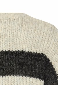 Close-up van gebreide stof met beige en zwarte horizontale strepen in een gemeleerd patroon.