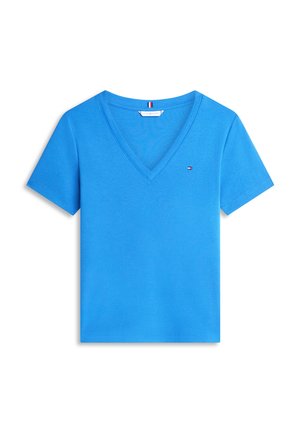 Blaues T-Shirt mit kurzen Ärmeln und V-Ausschnitt, mit kleinem roten, weißen und blauen Logo auf der linken Brust und Flaggen-Detail im Krageninnneren.