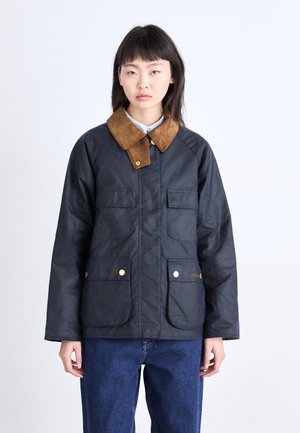 Veste bleu marine avec un col en velours côtelé marron, quincaillerie dorée et deux poches avant. Présente une coupe droite et une texture lisse.
