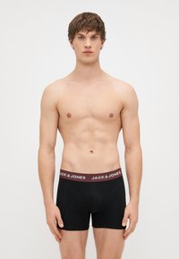 Μαύρα σλιπ με ελαστική ζώνη σε μπορντό χρώμα που φέρει το λογότυπο "JACK & JONES". Λείος ύφασμα, εφαρμοστή σχεδίαση και μεσαίου μήκους στυλ.