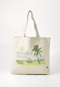 Tote bag laget av beige lerret med grafisk trykk som har en sol, palme og strandscene i blått og grønt. Lange stoffhåndtak.