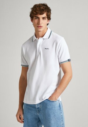 Polo blanco hecho de algodón texturizado, con un cierre de dos botones, cuello a rayas y puños con un logo en la manga.