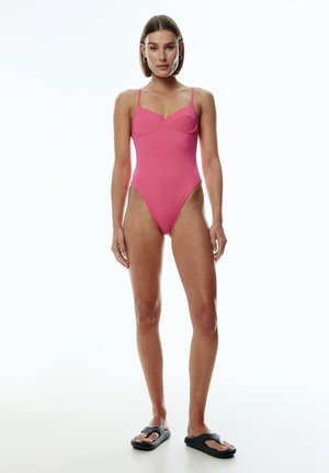 Roze badpak met dunne bandjes, voorzien van een sweetheart-halslijn en een hoge beenuitsparing. Glad textuur, minimale hardware, slank ontwerp.