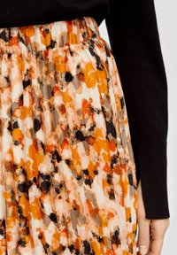 Plisserad kjol i lätt tyg med ett livligt, abstrakt mönster i orange, svart och creme. Elastisk midja för komfort.