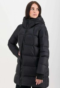 Zwarte gewatteerde jas met een hoge kraag, volledige rits en textuurpanelen. Beschikbaar met een capuchon en verborgen manchetten voor extra warmte.