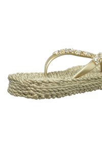 Sandale à plateforme beige tissée avec des brides dorées décorées de petits strass transparents, présentée en gros plan sur fond blanc.