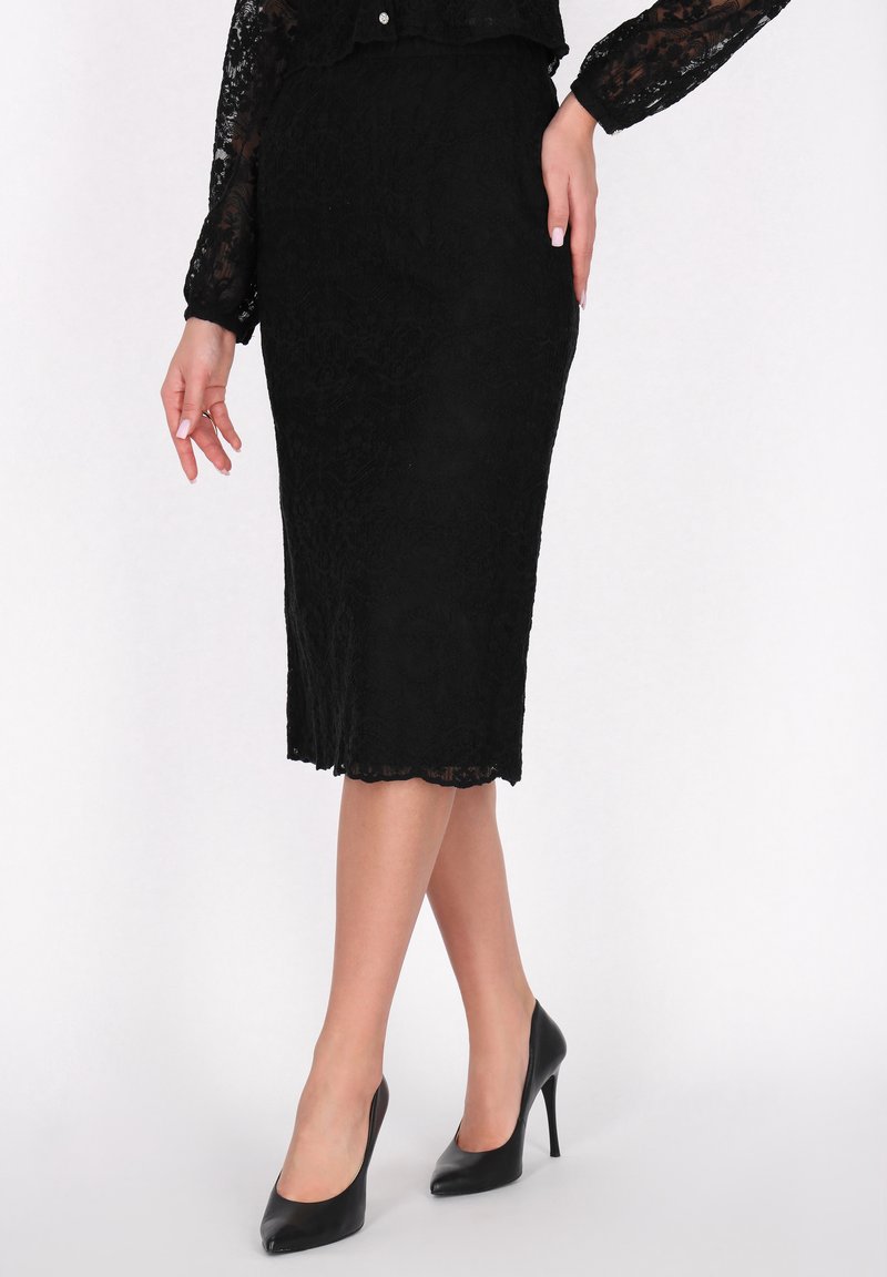 Schwarzer Spitze-Bleistiftrock mit gewelltem Saum; die taillierte Passform betont die Silhouette. Kombiniert mit schwarzen High-Heels.