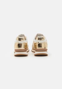 Gylne metalliske sneakers med hvite detaljer, med polstret krage, flate lisser og "1973" preget på hælen. Gummisåle for godt grep.