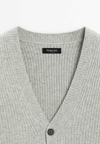 Cardigan en laine tricotée côtelée gris clair avec col en V, un seul bouton noir, et étiquette "Massimo Dutti" à l'intérieur du col.
