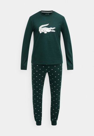 Groen top met lange mouwen en een witte krokodillenprint, gecombineerd met groene broek met kleine witte krokodillenpatronen. Zacht katoenmateriaal.