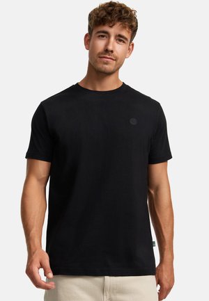 Svart bomull T-shirt med rund hals, korta ärmar och en liten, tonad logotyp på vänster bröst. Slät textur, klassisk passform.