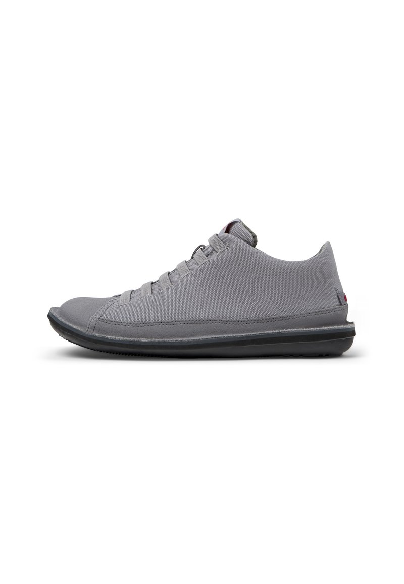 Šedá sportovní bota s texturovaným svrškem, plochou podešví a designem na šněrování. Disponuje minimalistickou konstrukcí a decentním logem na patě.