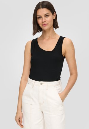 Schwarzes, geripptes Tanktop mit breiten Trägern, kombiniert mit hochgeschnittenen, cremfarbigen Hosen, die vordere Taschen und leichte Nähte aufweisen.