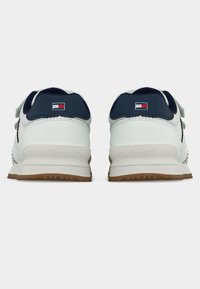 Άσπρα αθλητικά παπούτσια με ναυτικό μπλε λεπτομέρειες, υφή επιφάνειας, επίπεδη γόμα στη σόλα και μικρό λογότυπο στη φτέρνα. Διαθέτουν στρογγυλεμένη μύτη και κλασικό σχέδιο.