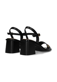 Czarne sandały na obcasie wykonane z teksturowanej skóry, z otwartym noskiem, paskiem w okolicy kostki i kwadratowym obcasem. Charakteryzują się subtelnym złotym akcentem.