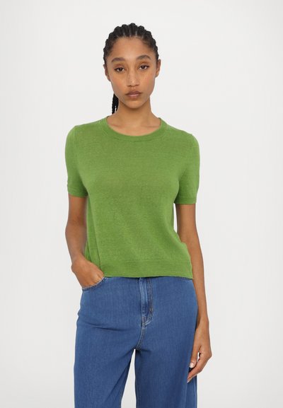 Grøn kortærmet strikket sweater med rund halsudskæring, blød tekstur og en afslappet pasform. Kombineret med blå denimjeans.