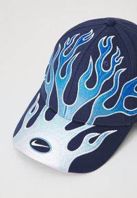 Boné azul marinho com padrões de chamas em tons de azul e branco. Logo na frente. Design clássico de boné de beisebol com aba curva.