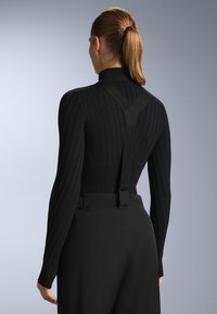 Černý žebrovaný rolák s nastavitelnými šlemi, texturovaná tkanina, přiléhavý design a bezproblémové přechody na kalhoty s vysokým pasem.