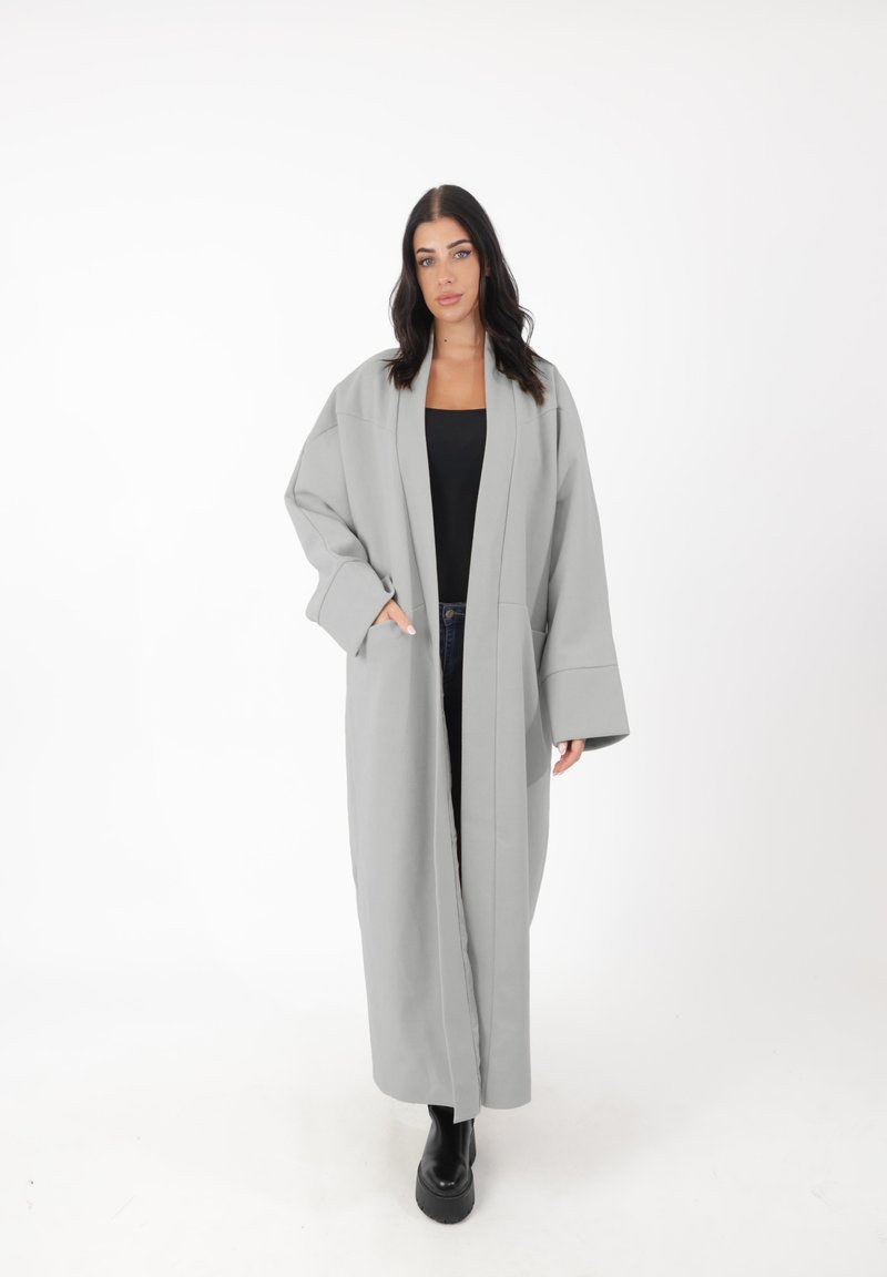 Langer grauer Mantel mit weiten Ärmeln und gerader Silhouette. Vordertaschen, aus einem strukturierten Stoff, offenes Design ohne Verschlüsse.