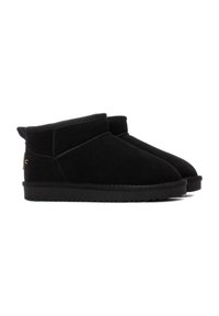 Botas de tobillo de ante negro con punteras redondeadas, costuras mínimas y suela de goma negra. Presentan un diseño con parte superior doblada y un sutil acento de marca.