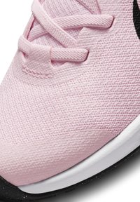 Jasnoróżowe buty sportowe z teksturowaną siateczką, płaskimi sznurowadłami i czarnym akcentem logo; zawierają białą podeszwę środkową i gumową podeszwę.