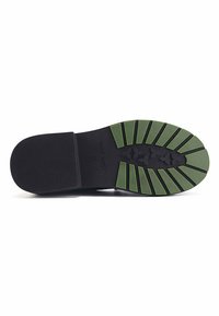 Shoe sole featuring a black rubber base with green traction ridges, textured for grip; marked with "NINE WEST" and size "37."