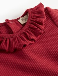 Top in tessuto rosso a coste con colletto a frange, dotato di chiusura a chiave sul retro e un'etichetta cucita all'interno.