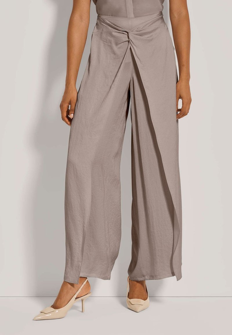 Lichtgrijze wijde broek gemaakt van zachte stof, met een gedraaide voorkant en een gladde textuur. Gecombineerd met nude hoge hakken.
