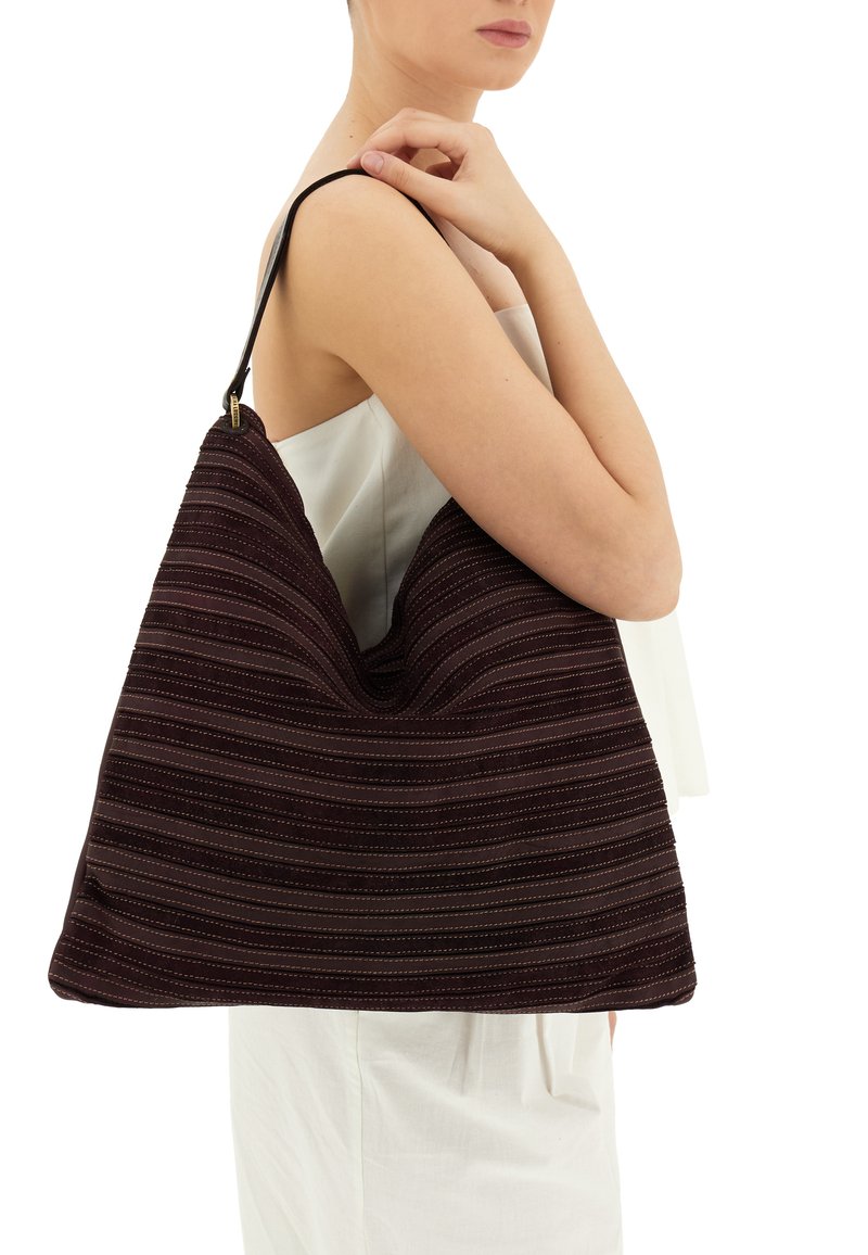 Borsa a spalla in tessuto a strisce viola con una forma morbida, caratterizzata da una tracolla in pelle nera e dettagli di cucitura discreti.