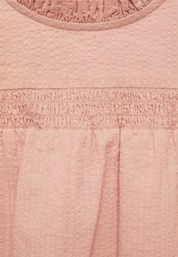 Tessuto rosa testurizzato con un motivo a trapunta, dettagli arricciati in vita e scollatura arrotondata.