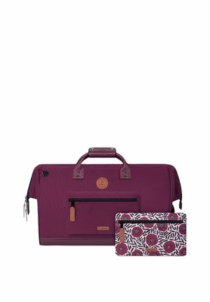 Grand sac de voyage violet avec poche zippée à l'avant et petite pochette assortie avec motif floral en violet, noir et blanc.