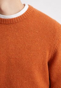 Orange gestrickter Pullover mit geripptem Rundhalsausschnitt, strukturierter Oberfläche mit subtilen, mehrfarbigen Sprenklern und lockerer Passform.