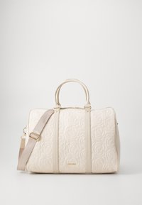 Sac matelassé beige avec motif floral, double anses supérieures, sangle ajustable et quincaillerie dorée. Texture lisse, design spacieux.