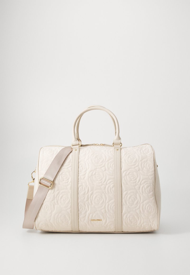 Sac matelassé beige avec motif floral, double anses supérieures, sangle ajustable et quincaillerie dorée. Texture lisse, design spacieux.