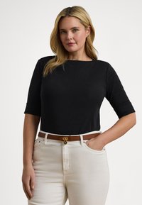 Μαύρο τοπ με κοντά μανίκια και στρογγυλή λαιμόκοψη, συνδυασμένο με κρεμ τζιν ψηλόμεσο και καφέ ζώνη με χρυσή αγκράφα.