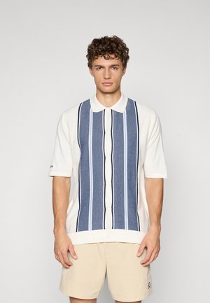 Kortermet skjorte med hvit kropp, prydet med vertikale striper i marineblått og lyseblått. Knappelukking foran og klassisk kragedesign.