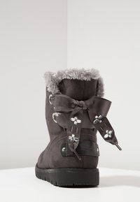 Botas de ante gris con cuello de pelo sintético, moño decorativo con acentos de flores y suela de goma negra. Presenta ojales metálicos para los cordones.