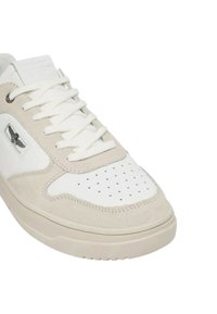 Sneaker in pelle bianca e camoscio beige con punta traforata, lacci bianchi piatti e piccolo logo sul lato. Suola in gomma arrotondata.